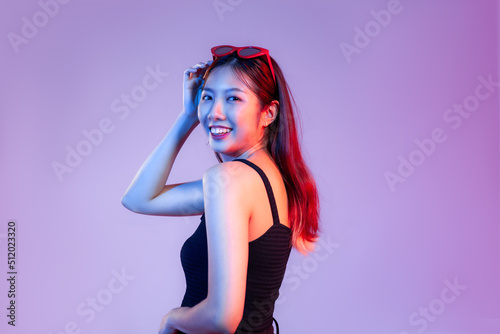 Young asian woman in black tank top posing smilling on purple background.