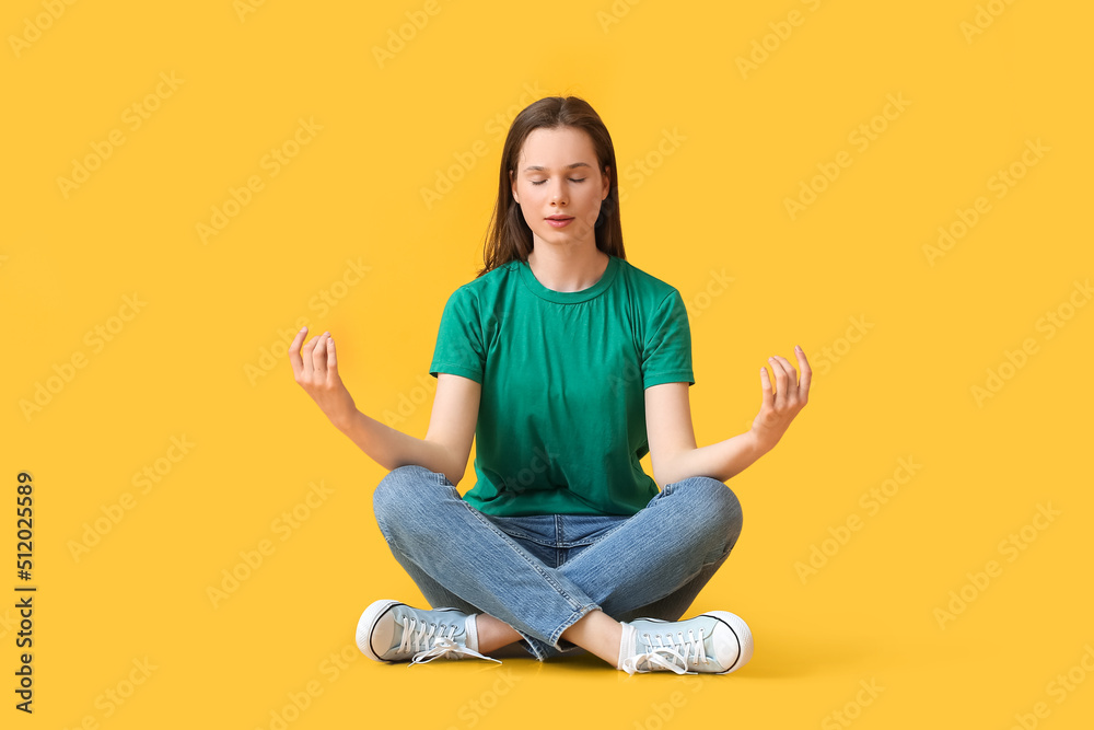 Pretty young woman meditating on yellow background Pretty young woman meditating on yellow background