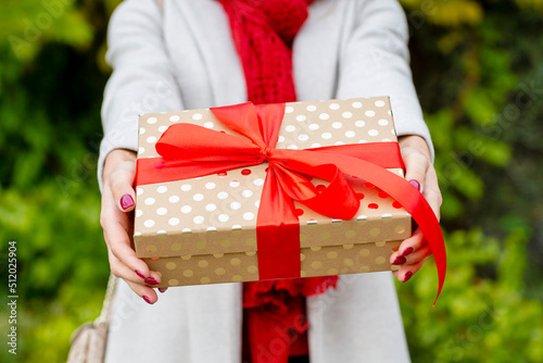 Young woman giving Christmas present with red bow