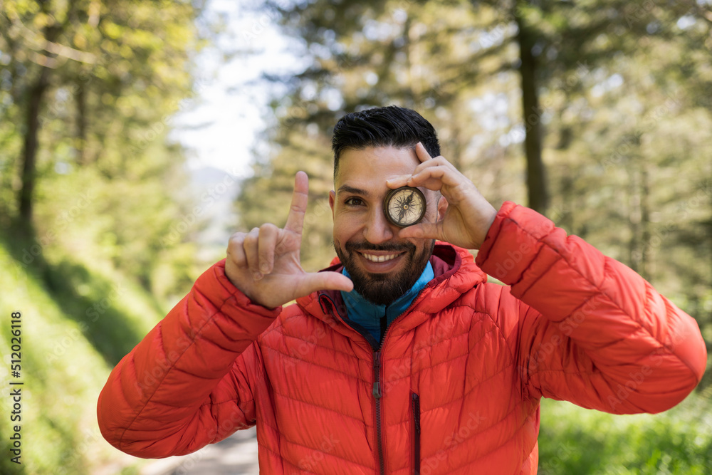 Happy man covering eye with navigational compass Happy man covering eye with navigational compass