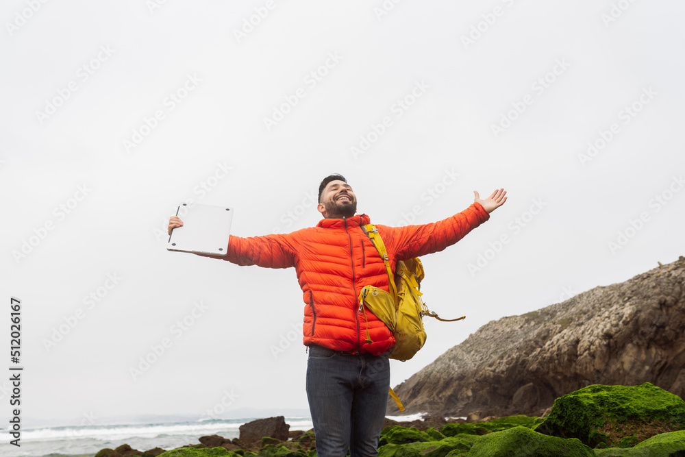 Smiling man wearing backpack standing with arms outstretched Smiling man wearing backpack standing with arms outstretched