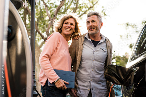 Smiling mature couple looking at charging station photo