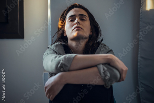 Lonely and sad woman with eyes closed leaning on wall at home photo
