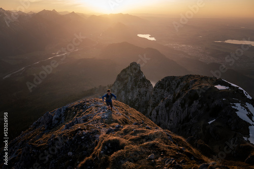 Hiker moving up on mountain peak at sunset photo