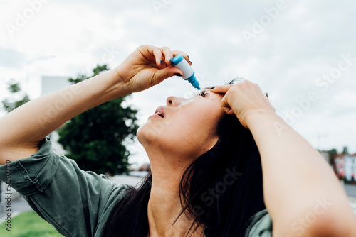 Young woman putting drop in eye photo