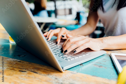 Hands of freelancer typing on laptop at sidewalk cafe photo