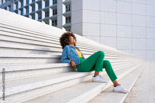 Smiling woman with eyes closed sitting on steps photo