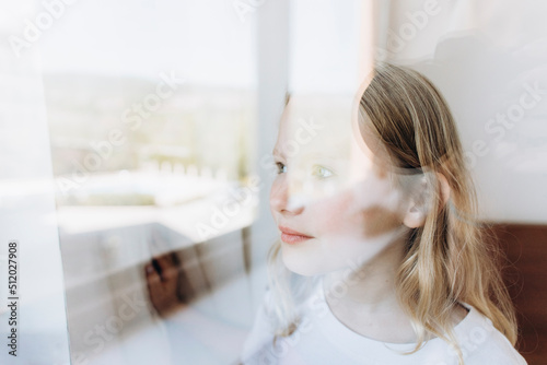 Contemplative girl looking through window photo