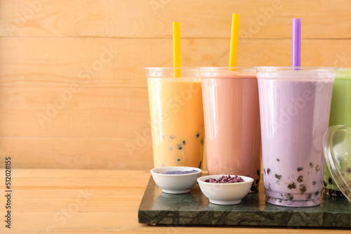 Board with plastic cups of different tasty bubble tea on table