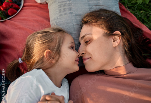 Smiling mother and daughter rubbing noses at picnic in field photo