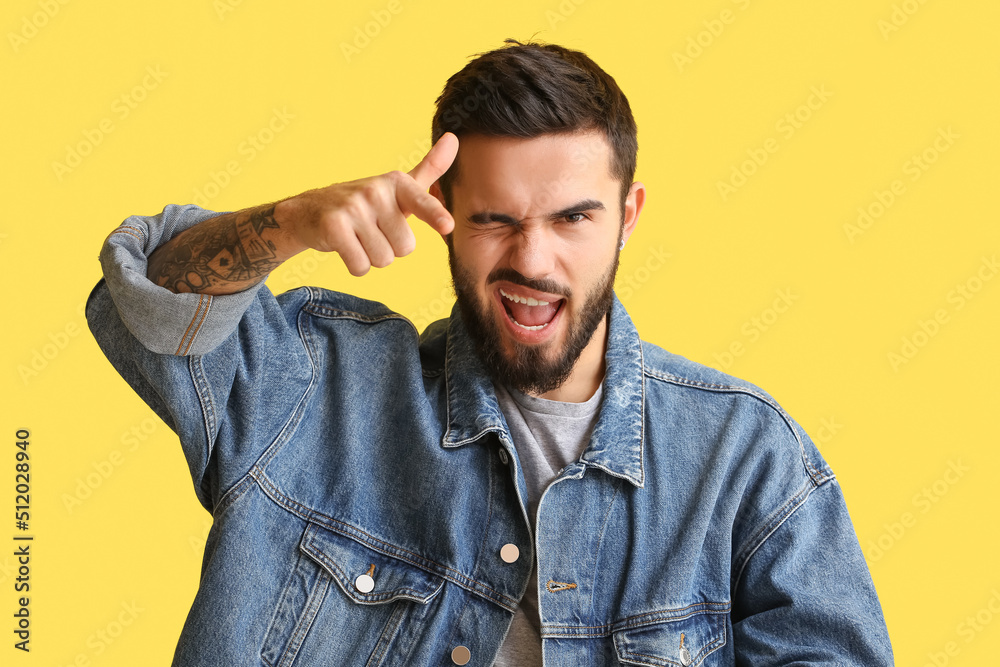 Bearded man pointing at viewer and winking on yellow background