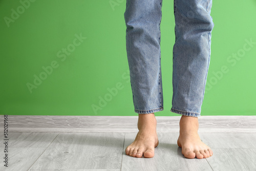 Young barefoot man near green wall
