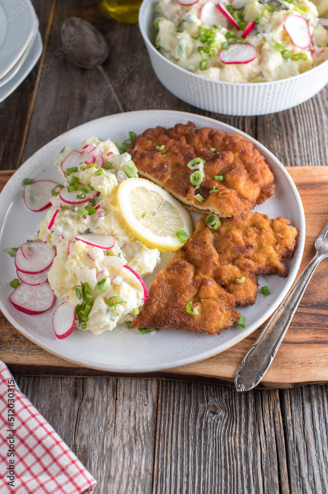 Breaded chicken schnitzel with light potato salad on a plate Breaded chicken schnitzel with light potato salad on a plate