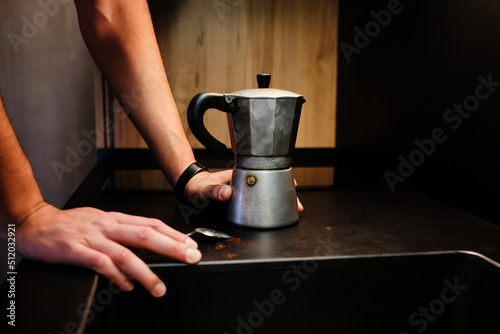 Hands of man by moka coffee maker on table