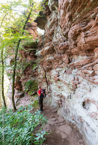 Germany, Rhineland-Palatinate, Senior hiker on trail along red sandstone rock formation in Palatinate Forest photo