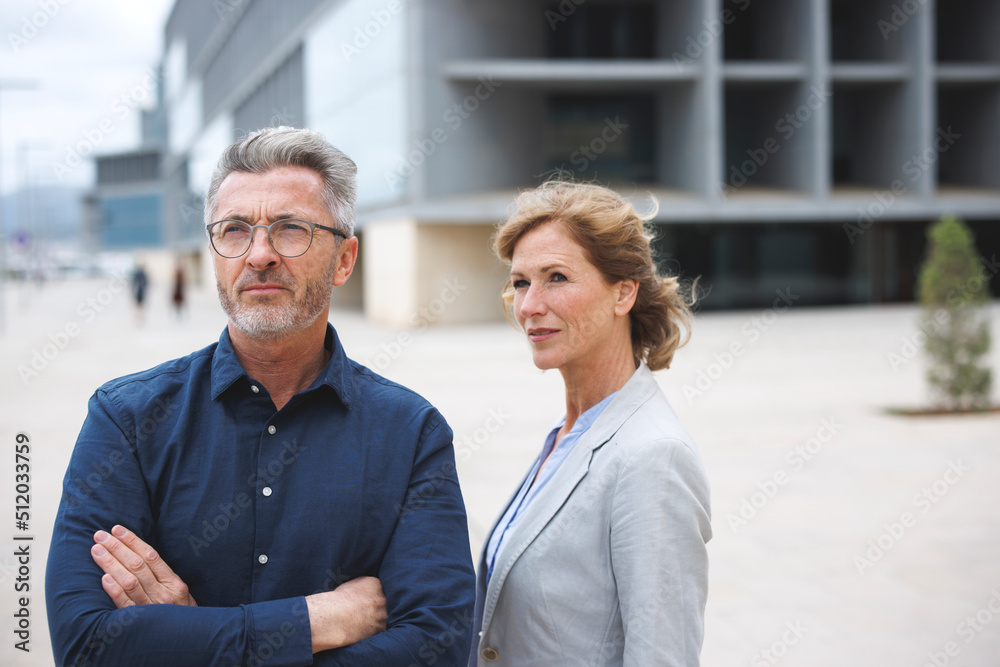Businessman with arms crossed standing by businesswoman Businessman with arms crossed standing by businesswoman