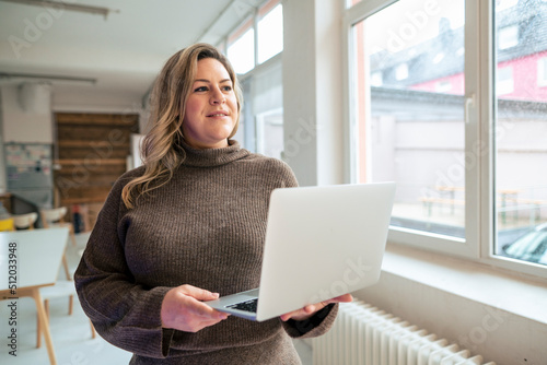 Thoughtful plus size businesswoman with laptop at office photo