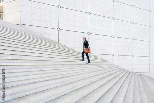 Businessman with bag moving up on steps