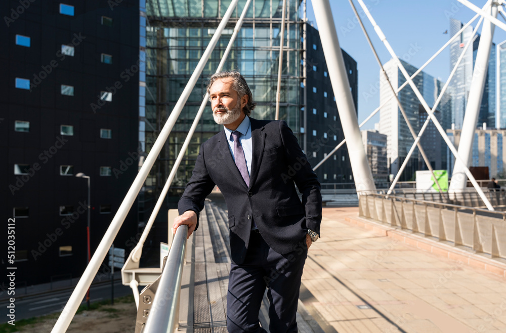 Businessman with hand in pocket standing by railing on sunny day Businessman with hand in pocket standing by railing on sunny day