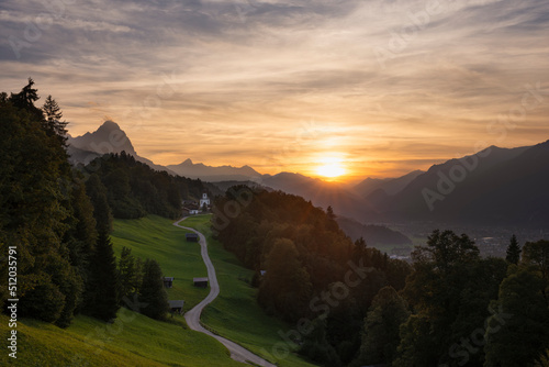 Germany, Bavaria, Wamberg, Sun setting over small road leading to remote village in Wetterstein mountains photo