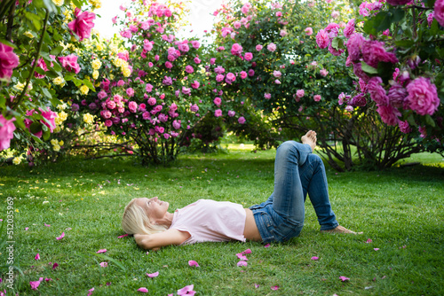 Woman with hands behind head lying on grass at garden photo