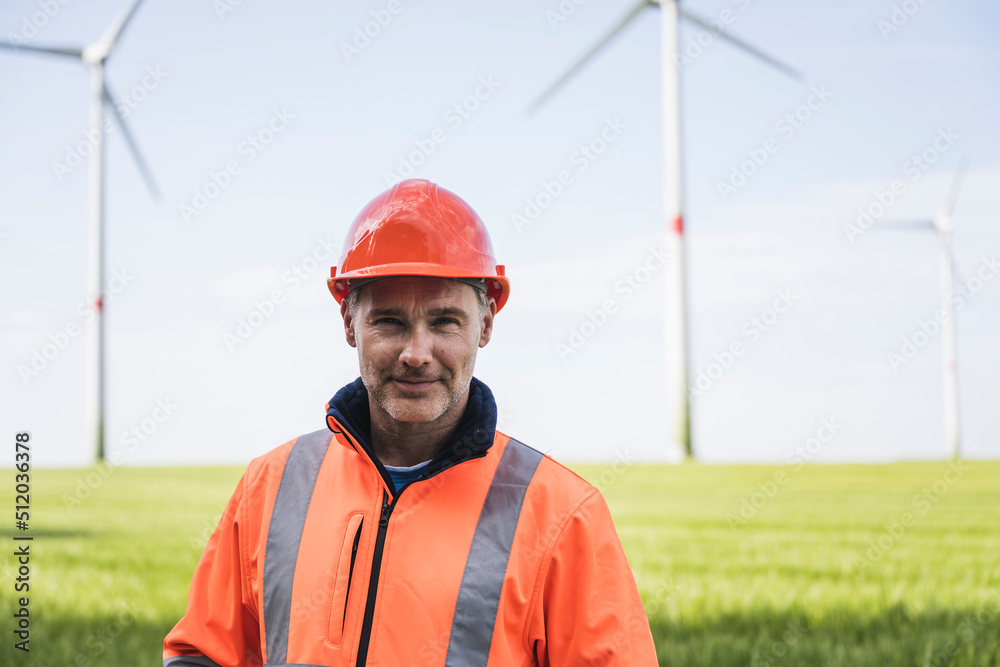 Smiling engineer wearing hardhat standing on field Smiling engineer wearing hardhat standing on field