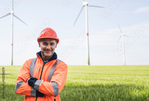 Smiling engineer with arms crossed standing on field photo