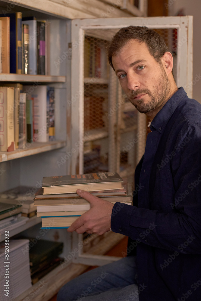 Man arranging books in shelf at home Man arranging books in shelf at home