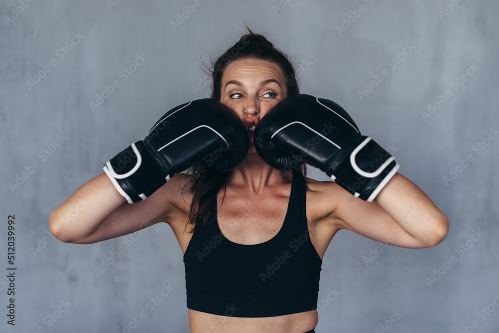Young woman boxer jokingly beats herself.