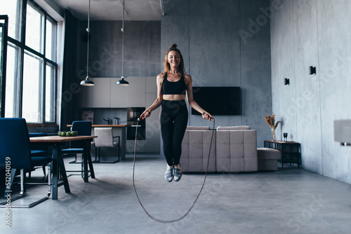 Fit woman with jump rope at home doing skipping workout. photo