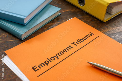 Documents for employment tribunal near a yellow folder.