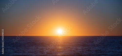 Sunset over sea with golden dramatic sky panorama. Calm sea with sunset sky. Ocean and sky background.