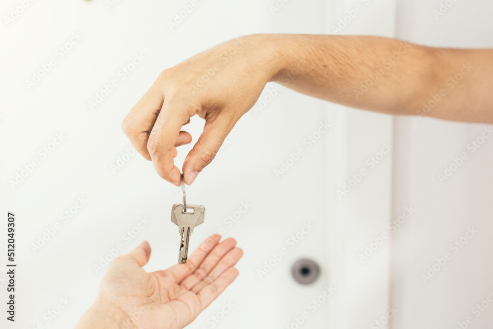 Hands of real estate agent giving house key to woman Hands of real estate agent giving house key to woman