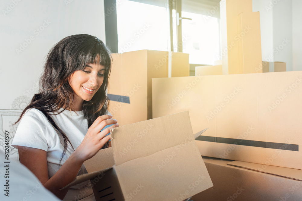 Smiling woman with cardboard box sitting at new home