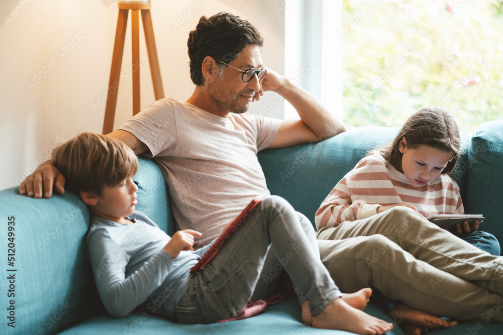 Mature man sitting with daughter and son using tablet PC at home Mature man sitting with daughter and son using tablet PC at home