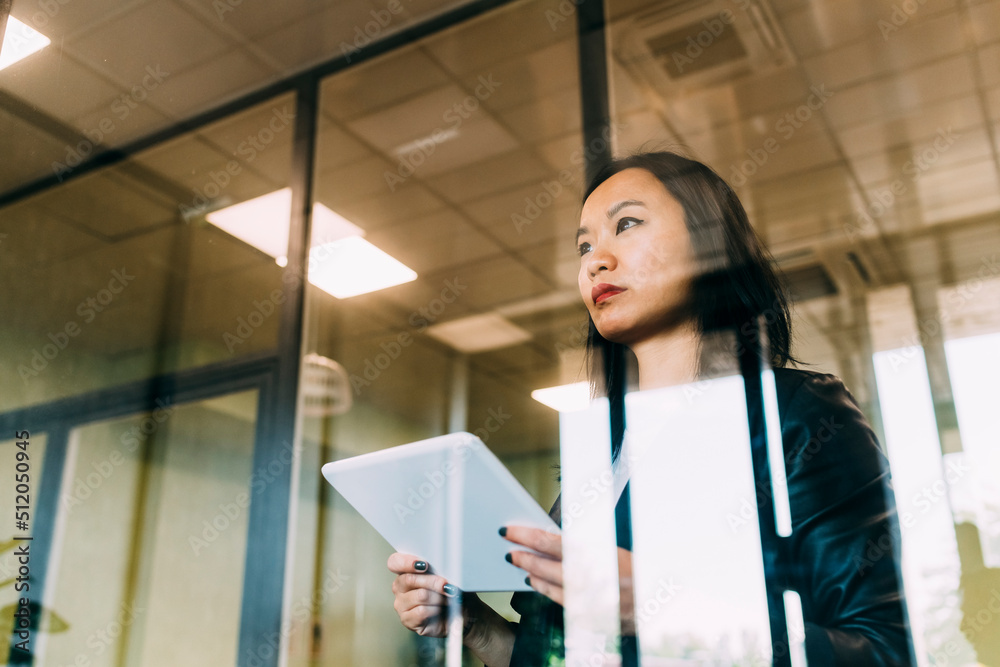 Confident businesswoman with tablet PC seen through glass at office Confident businesswoman with tablet PC seen through glass at office