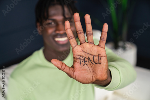 Smiling man showing peace written on palm of hand