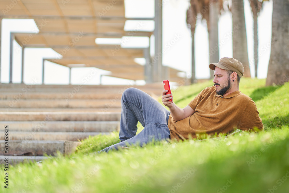 Relaxed man lying on the grass using the phone