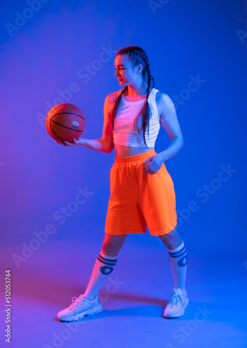 a girl with a basketball in orange shorts, a t-shirt and a baseball cap. sportswoman in golfs and sneakers on a blue background. Physical education teacher. basketball player © Ольга Новицкая