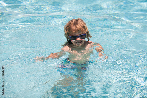 Kid in swimming pool. Funny cute little boy in sunglasses in pool in sunny day.