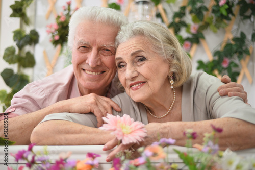 Happy elderly couple on the porch with flowers