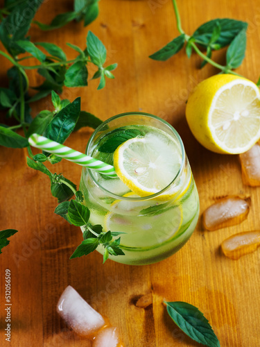 A glass of cucumber cold detox lemonade with mint and lemon on a wooden table