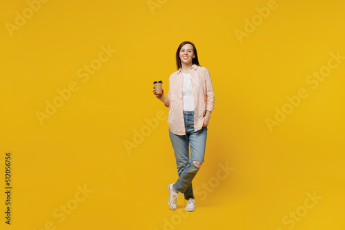 Full body young happy woman she 30s wears striped shirt white t-shirt hold takeaway delivery craft paper brown cup coffee to go isolated on plain yellow background studio. People lifestyle concept