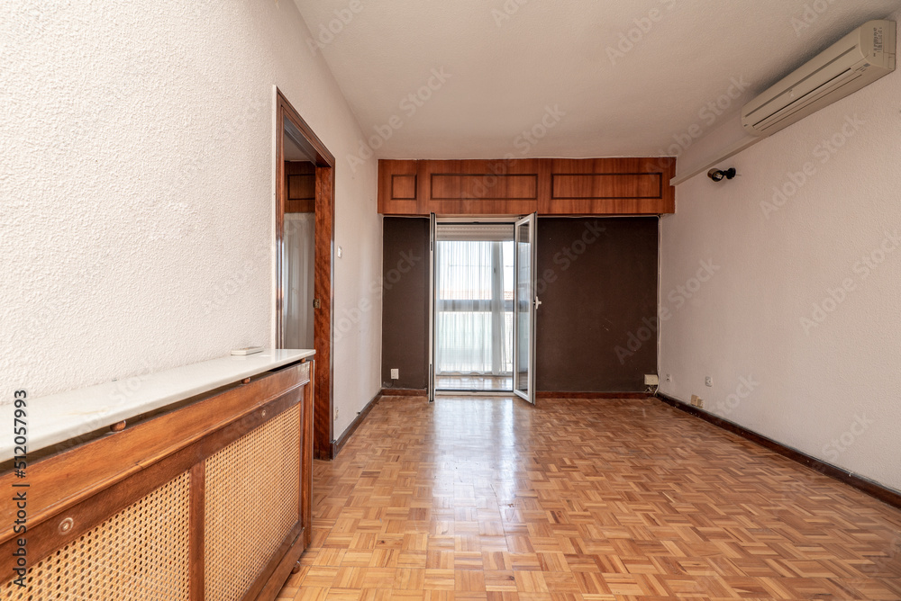 Obraz premium Empty living room with oak parquet floors, wooden radiator cover and white and brown painted walls