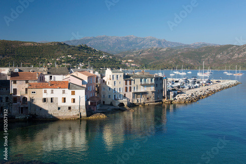 View over rooftops from the citadel ramparts, waterside houses reflected in calm sea, St-Florent, Haute-Corse