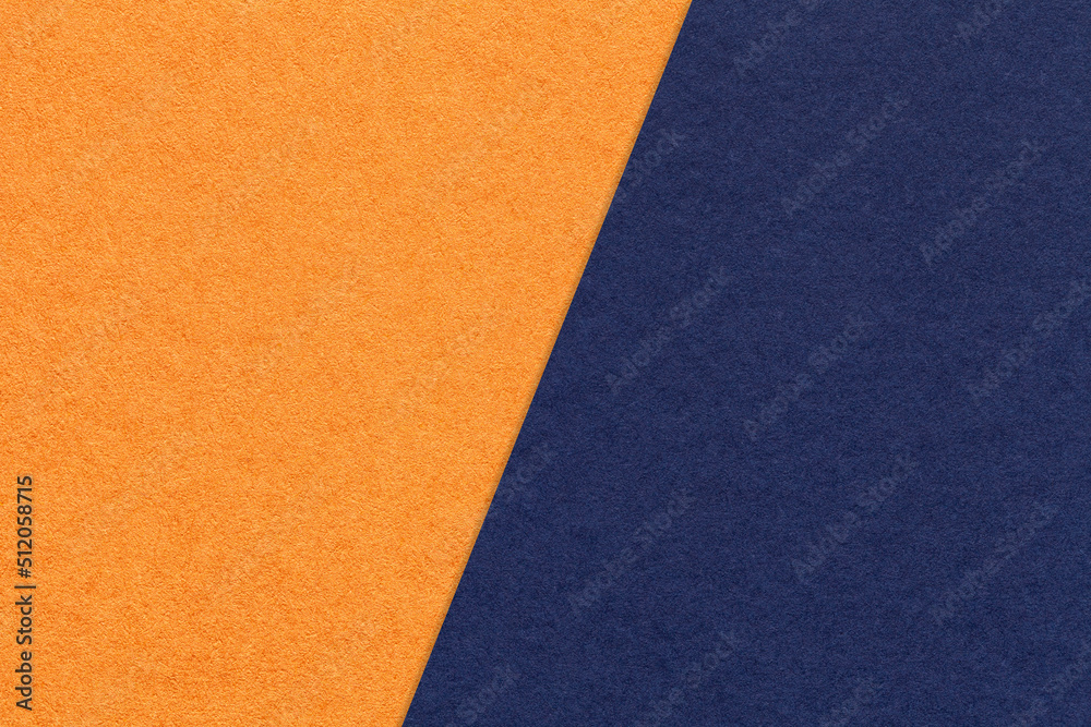 Fototapeta premium Texture of craft orange and navy blue paper background, half two colors, macro. Structure of craft indigo cardboard.