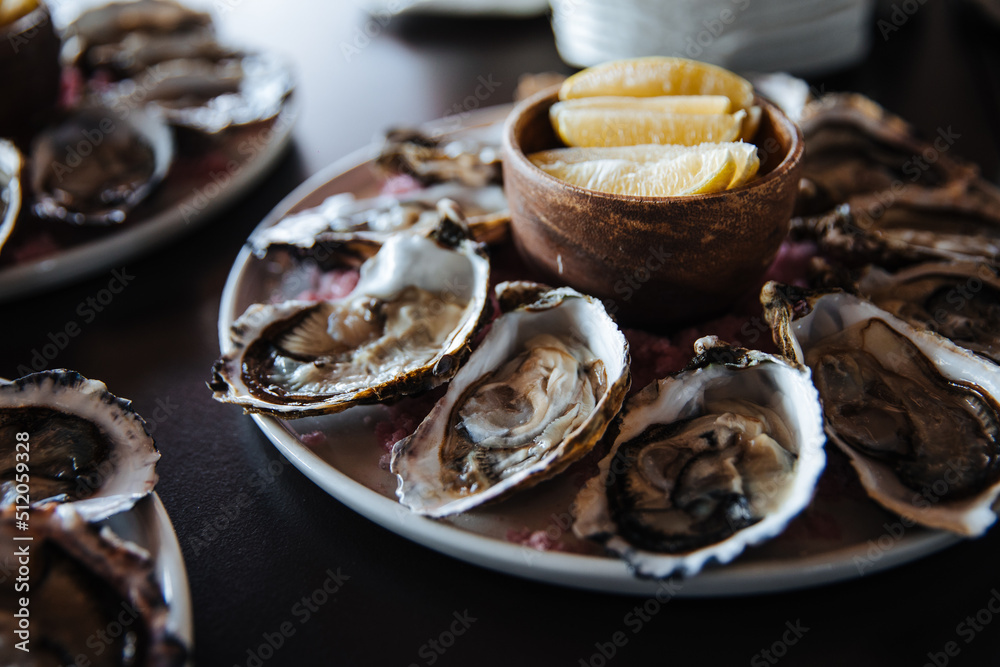 Fresh oysters on plate, served table with oysters, lemon in restaurant. Gourmet food Fresh oysters on plate, served table with oysters, lemon in restaurant. Gourmet food