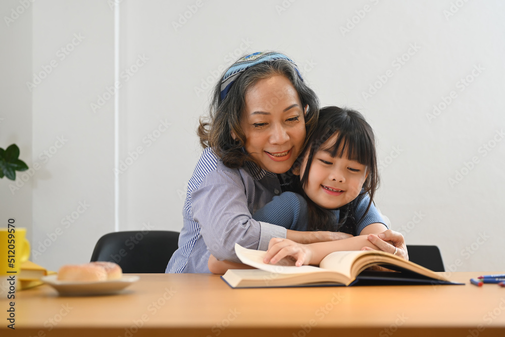 Caring grandma telling story, reading fairy tale to her little granddaughter. Multi generational, family and love concept Caring grandma telling story, reading fairy tale to her little granddaughter. Multi generational, family and love concept