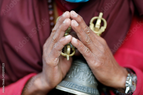 Buddhist monk (lama) in traditional robes holding ritual attributes of Buddhism, rosary, vajra, bell, Pema Osel Ling Monastery, Kathmandu, Nepal photo