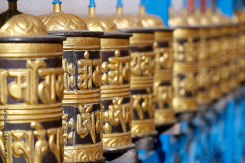 Rolling metal prayer wheels circling, with mantra written in Tibetan language, Shakhya Tharig Buddhist Monastery, Kathmandu, Nepal photo